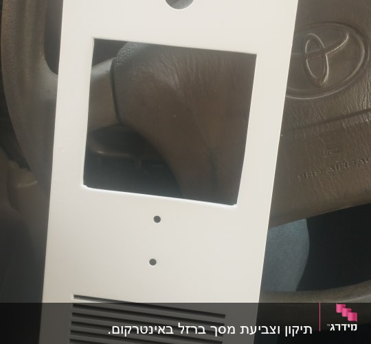 מסגרת לבנה עם חורים ומגרעות על רקע הגה רכב
